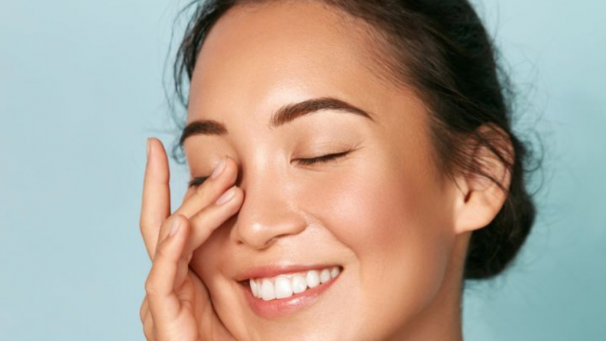 Bright and glowing skin with a person applying moisturizer on their face, surrounded by dry, windy harmattan conditions. The image represents skincare tips for maintaining hydration and protection during the harmattan season.